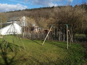 an empty swing set in a yard with a house at Gîte dix-huit in Les Hayons