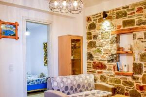 a room with a stone wall with a couch and a chair at Klaidis house in Skiathos