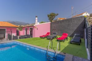 un patio trasero con piscina y sillas y una casa en Villa Rosa with private pool by HR Madeira, en Ribeira Brava
