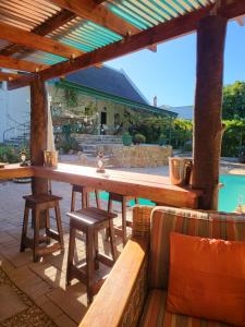 a wooden table and benches on a patio with a pool at Rosenhof Garden Cottage in Clanwilliam