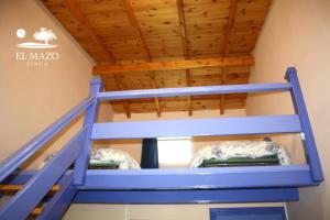 a loft bed in a room with wooden ceilings at Albergue Finca El Mazo in Rada