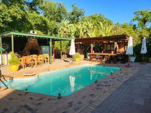 a swimming pool with a table and chairs and umbrellas at Rosenhof Garden Cottage in Clanwilliam