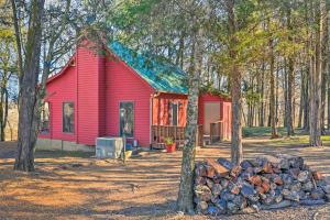 a red house with a pile of logs in front of it at Serene Cabin with Riverfront Views and Access! in Fayetteville