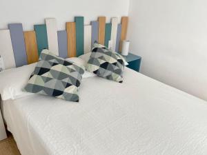 ein Bett mit zwei Kissen und einem Kopfteil aus Holz in der Unterkunft Sea Soul Apartment Puerto Santiago in Puerto de Santiago