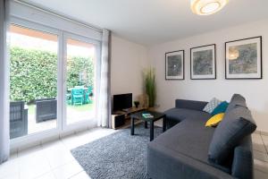 sala de estar con sofá y puerta corredera de cristal en My Cozy Flat Blagnac - T2 - Free Parking - Terrasse - Jardin, en Blagnac