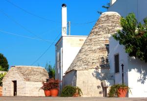 a white building with a chimney and two plants at Dimora Sumerano in Alberobello