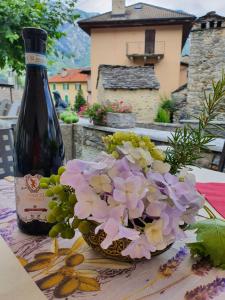 Antica Osteria Ghiridone في Palagnedra: زجاجة من النبيذ للجلوس بجوار وعاء من الزهور