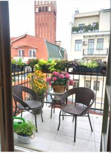 エルブロンクにあるBea Home Elblag - dwie sypialnieのパティオ(椅子、テーブル、花の鍋付)