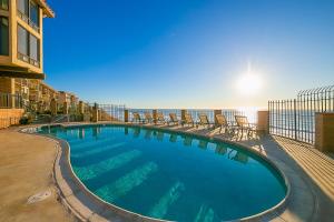a swimming pool with chairs and the ocean in the background at Oceanfront Condo, Hot Tub, Heated Pool, Beach Access, Beach Gear in Solana Beach