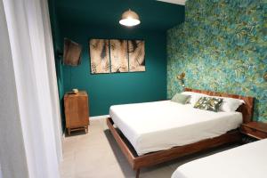 1 dormitorio con 2 camas y pared verde en Ross Family Suites, en Reggio Calabria