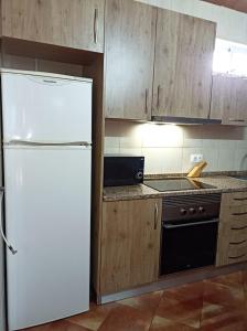 cocina con nevera blanca y armarios de madera en Casa Ponto de Encontro en Almodôvar