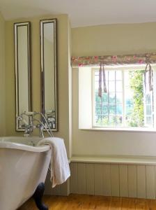 a bathroom with a tub and a window at Old Mutlow Cottage in Longhope