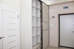 a walk in closet with white shelves and a door at Отдельная квартира с видом на Ботанический садWiFi in Bishkek