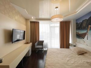a bedroom with a bed and a tv and a chair at Most City Center Studio Apartment in Dnipro