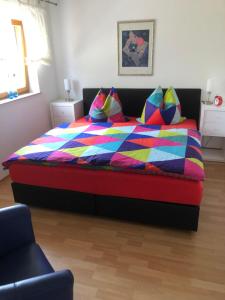 ein Schlafzimmer mit einem Bett mit einer bunten Bettdecke und Kissen in der Unterkunft Ferienwohnung am Rohrbacherhof Sabine Rück in Barackenhöfe