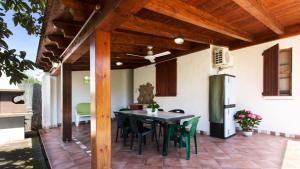 a patio with a black table and green chairs at Case Vacanza Aiosardegna Porto Columbu in Porto Columbu - Perdʼe Sali
