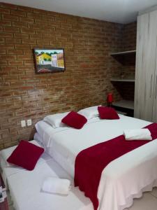 two beds in a room with a brick wall at Pousada Baobá in Olinda