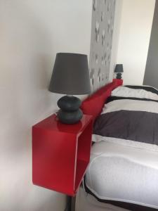 una mesita roja con una lámpara junto a una cama en Silver Apartman, en Harkány