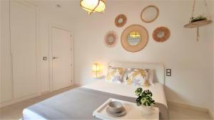 biała sypialnia z łóżkiem i lustrami na ścianie w obiekcie Apartamento San Nicolás - tranquilidad y comodidad en el centro de Murcia w Murcji