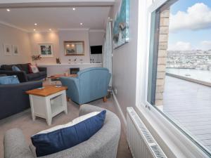 een woonkamer met een bank en stoelen en een groot raam bij Moorings in Dartmouth