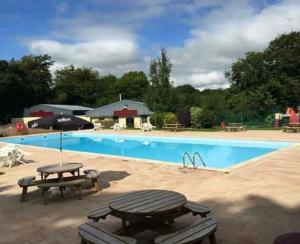 a large swimming pool with a picnic table and benches at Holiday Cabin Sleeps 5 Glan Gwna Holiday Park in Caernarfon