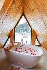 ein Badezimmer mit einer weißen Badewanne mit roten Rosenblättern darauf in der Unterkunft Cozy Cabin A Frame in Topliţa