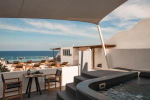 a resort with a swimming pool and tables and chairs at Almyra Oia Suites in Oia