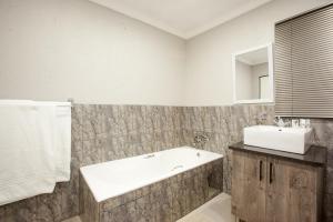 a bathroom with a bath tub and a sink at Windmills Rest in Pretoria