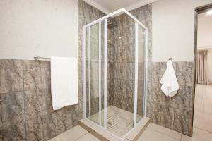 a shower with a glass door in a bathroom at Windmills Rest in Pretoria