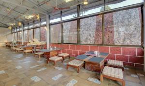 restauracja ze stołami i krzesłami oraz dużymi oknami w obiekcie Treebo Trend Jeevan Village w mieście Panchgani