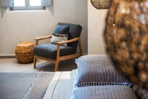 a bedroom with a blue chair and a bed and a chairuggest at Almyra Oia Suites in Oia