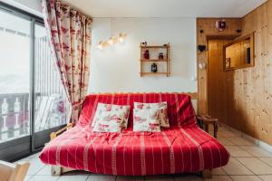 a red bed in a room with a window at Apartment with balconies ski-in ski-out classified 2 stars in Saint-Gervais-les-Bains