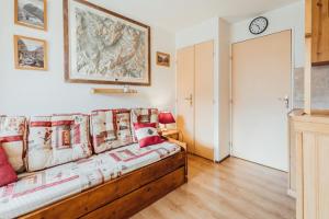 a bedroom with a couch and a clock on the wall at Furnished studio at the foot of the slopes with a balcony & mountains view in Saint-Gervais-les-Bains