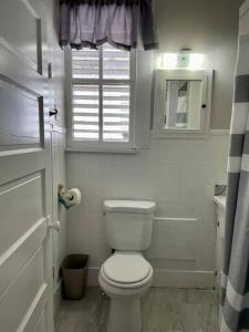 a white bathroom with a toilet and a window at Surf Shack on 24th in Galveston