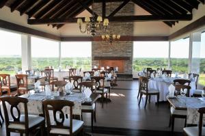 a dining room with tables and chairs and windows at Altos del Arapey All Inclusive, Golf & Spa in Termas del Arapey