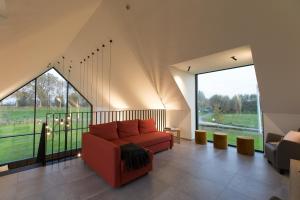 Vakantiewoning Trimaarzate في Zwevegem: غرفة معيشة مع أريكة حمراء ونوافذ كبيرة