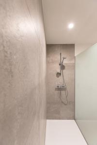 een douche in een badkamer met een betonnen muur bij Vakantiewoning Trimaarzate in Zwevegem