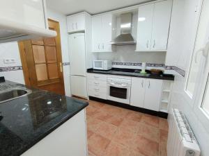 uma cozinha com armários brancos e um forno com placa de fogão em EL RINCÓN DE BLASA em Cazorla