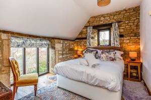 a bedroom with a bed and a stone wall at The Stables in Chipping Campden