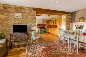 a living room with a table and chairs and a television at The Stables in Chipping Campden