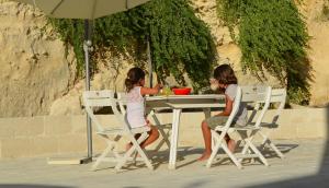 Due ragazze sedute a un tavolo sotto un ombrello di La Casa Del Gelso Bianco a Otranto