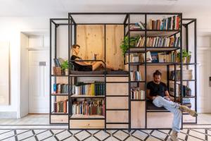 a man and a woman sitting in a book shelf at Selina Neve Tzedek Tel Aviv in Tel Aviv