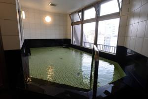 una piscina de agua en una habitación con ventana en Natural Hot Spring Midosuji Hotel, en Osaka