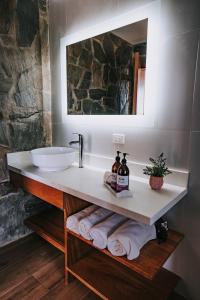 a bathroom with a sink and a mirror and towels at Siempre Valle Hotel Boutique in Valle de Guadalupe