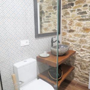 a bathroom with a toilet and a sink and a stone wall at Casa Leonor de Aurora in Zas