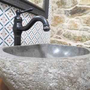 lavabo de piedra con grifo negro en el baño en Casa Leonor de Aurora, en Zas