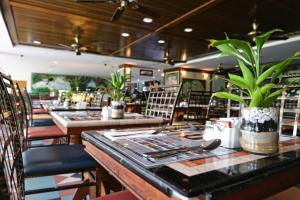 a restaurant with wooden tables and chairs and plants at Holiday Villa Resort & Beachclub Langkawi in Pantai Cenang