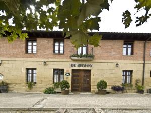 a brick building with a brown door and windows at Casa Rural El Meson in Briones