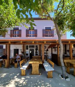 een picknicktafel en banken voor een gebouw bij Hostel Jadran in Pag