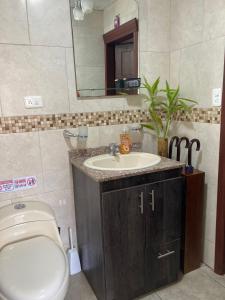 a bathroom with a sink and a toilet and a mirror at Panchi´s House in Baños